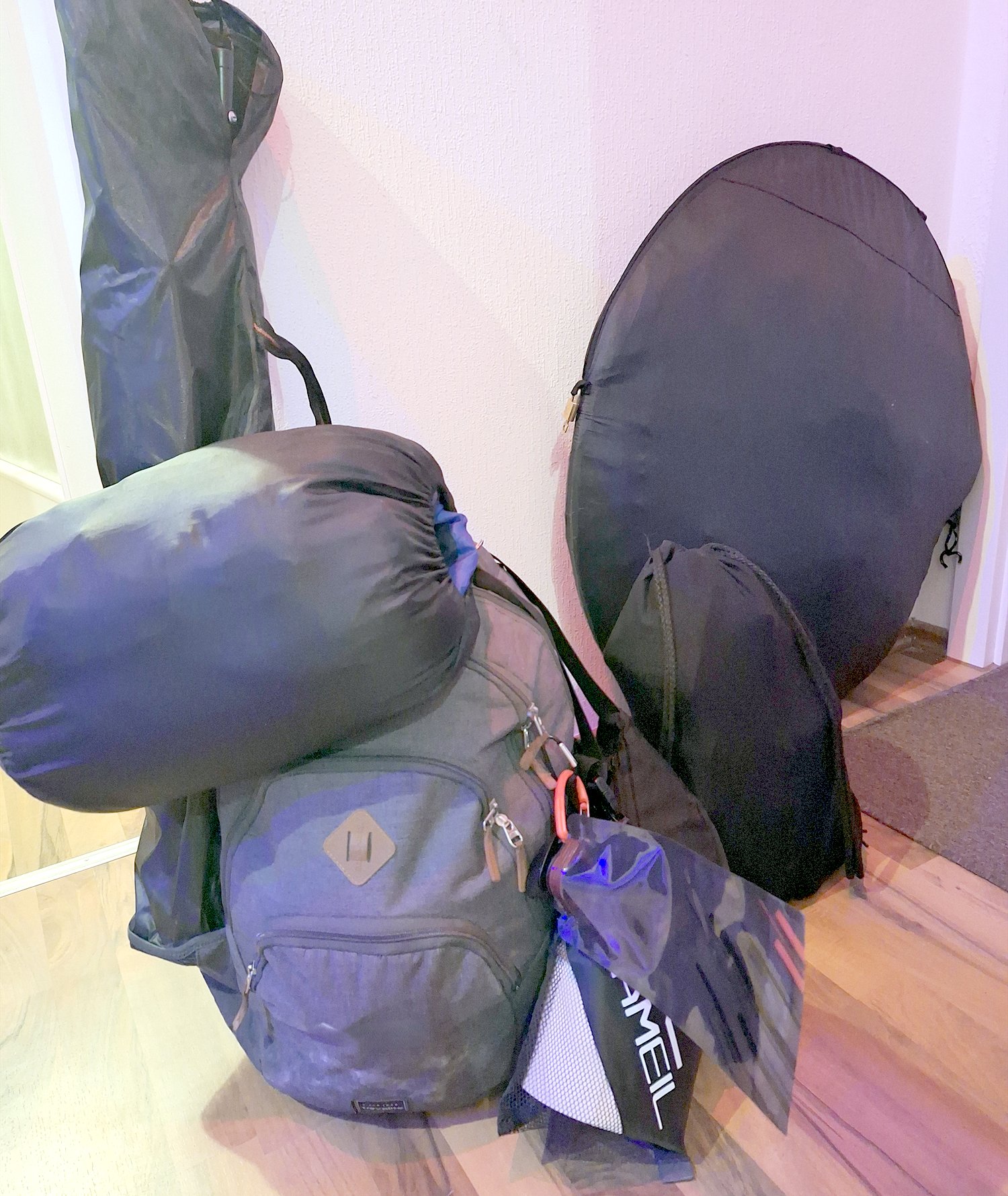 Gepäck für ein Festivalwochenende im Flur: Rucksack, Schlafsack im Packsack, Wurfzelt in der runden Tragetasche, Pavillontasche und Campingstuhl.